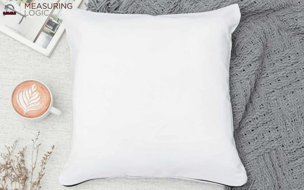 An 18x18 inch throw pillow resting beside cup of coffee