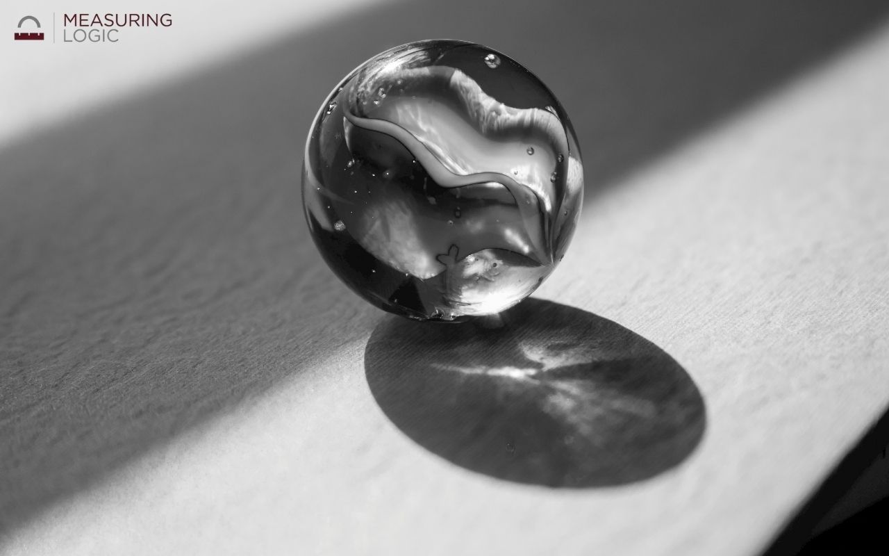 shooting marble casting a shadow on a textured surface, a common household item close to 1 inch in diameter