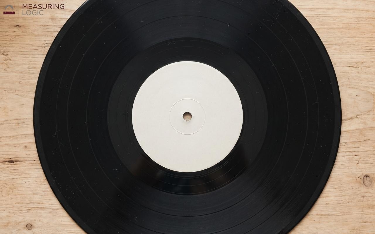 A classic black vinyl record with a white center label resting on a wooden surface.
