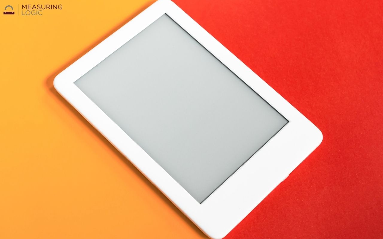 A white e-reader resting diagonally on a split orange and red background.