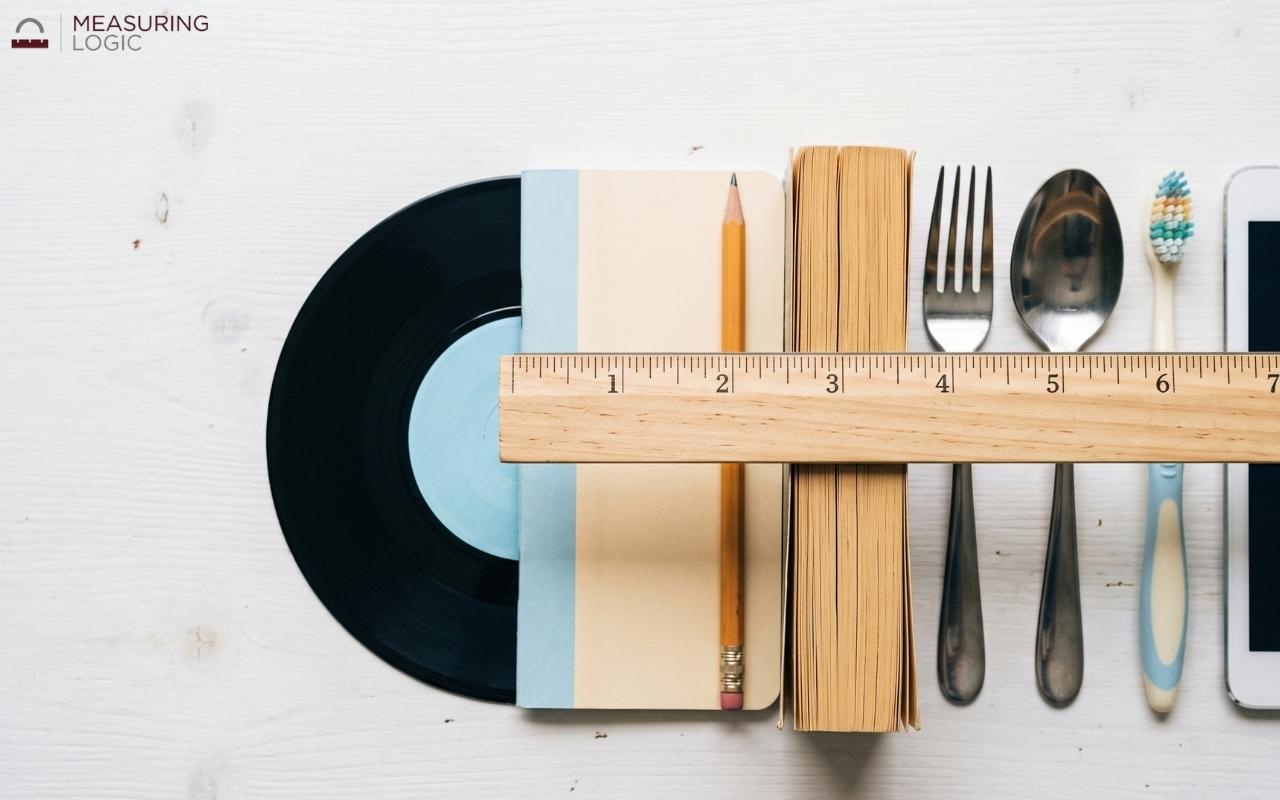 Top-down view of everyday objects with a wooden ruler placed next to them to visualize 7 inches.