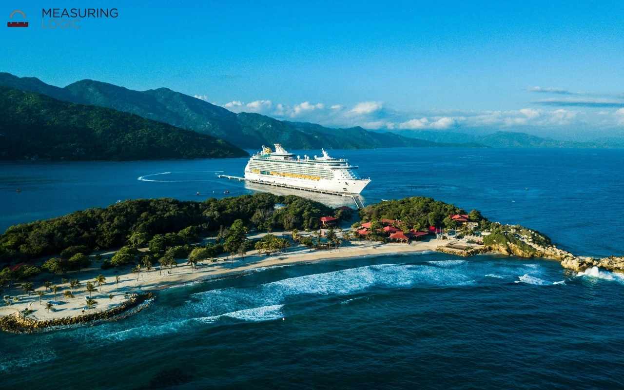 Aerial view of a large cruise ship near a tropical island, stretching over 500 feet long